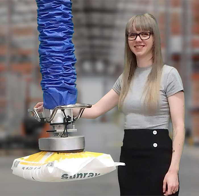 Vacuum sack lifter with top-mounted suction gripper lifting a heavy-duty bag for industrial handling